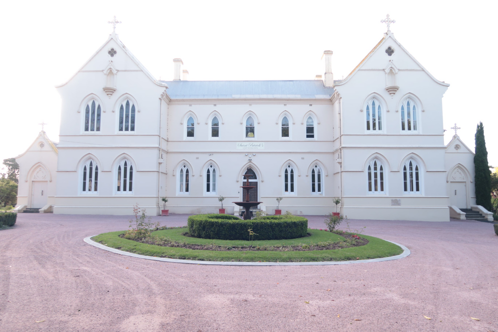 The Majestic Convent at Koroit, a grand historic building surrounded by lush greenery, featuring classic architectural design with tall windows, a gabled roof, and a peaceful atmosphere reflecting its serene past.